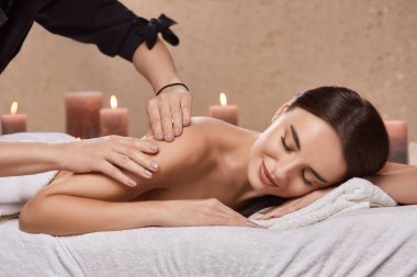 attractive woman lying with naked back in spa and having massage for her arms, beautician massaging arms for amazing girl in beauty salon 