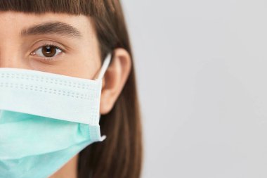 Korunan aseptik maskeli kadın kameraya bakarken covid-19, fotokopi alanı, steril koruyucuyla korunan genç insan Coronavirus 'taki kameraya bakıyor.