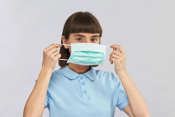 Jovem Mulher Colocando Máscara Proteção Olhando Para Câmera Isolada Cinza — Fotografia de Stock