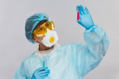 Laboratuvar doktoru koruyucu kostüm ve sarı gözlüklerle biyolojik tehlikeleri kontrol ediyor.