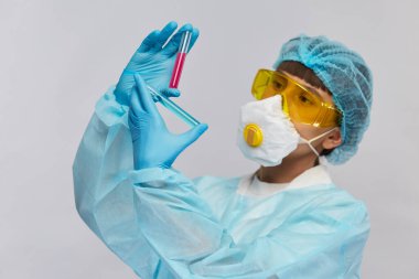 Biyokimyacı koruma gözlüklerinde farklı mavi ve kırmızı renkli iki büküm tüp analiz ediyor.