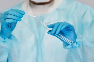 Doktor kollarının mavi tek kullanımlık eldivenlerle yakın plan çekimini test tüpünden örnek alın.