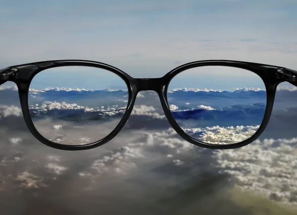 Clear vision through glasses on blue clouds landscape — Stock Photo, Image