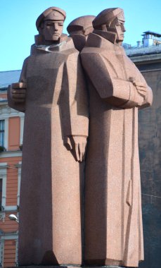 RIGA LATVIA 17 09 2015: Old Riga 'nın merkezinde, bazıları Lenin' in kişisel korumaları olan Letonya Kızıl Tüfeği 'ne adanmış tartışmalı bir kırmızı granit heykel duruyor..