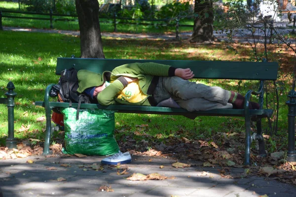 公園のベンチで寝てるホームレスの男 — ストック写真