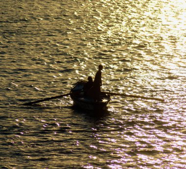Geleneksel Mısırlı bedevi balıkçı silueti. Gün batımında Nil nehrinde kürek çeken balıkçı.
