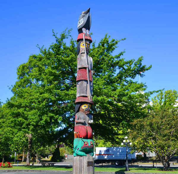 VICTORIA BC CANADA JUNE 23 2015: Totem pole site in front the historic british columbia province parliament building (built in 1893), victoria , BC, Canada