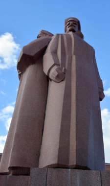 RIGA LATVIA 17 09 2015: Old Riga 'nın merkezinde, bazıları Lenin' in kişisel korumaları olan Letonya Kızıl Tüfeği 'ne adanmış tartışmalı bir kırmızı granit heykel duruyor..