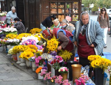 LVIV UKRAINE 09 09: 17: Yaşlı kadın babuşka, Lviv Ukrayna 'nın eski şehir merkezindeki pazarda yaşamak için çiçek satıyor.