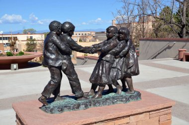 Santa Fe, Nm Usa 21 Nisan: 21 Nisan 2014 'te Santa Fe, Nm' de üç kız ve iki erkek çocuğun halatsız halat çekme oyunu oynadığı bronz heykel. Glenna Goodacre Lubbock, Teksas, 1939, Amerikan heykeltıraş.