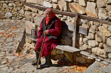 KOPRIVSHITSA BULGARIA 25 Eylül: 25 Eylül 2013 tarihinde Bulgaristan Koprivshtitsa 'da taş duvar üzerinde oturan yaşlı kadın
