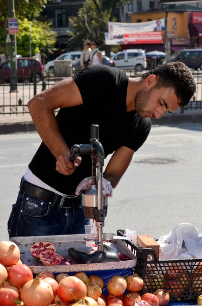 ISTANBUL TURKEY SEPT 28: Young man sells pomegranate juice for to live in down town Istanbul on september 28 2013. Pomegranate juice is one of the most popular in Turkey