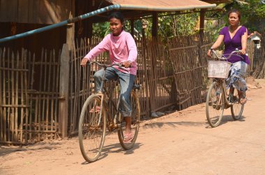 Phnom Phen, Kamboçya 23 Mart 2013: Kamboçya 'nın Phnom Phen şehrinde tanımlanamayan bir sokak çocuğu bisikleti sürüyor. Sadece Phnom Penh' de 10 ila 20 bin arasında çocuk yaşıyor ve sokaklarda çalışıyor.