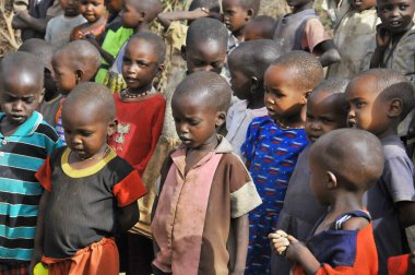 AMBOSELI, KENYA - 13 Ekim 2011 Masai Mara, Kenya 'da inek gübresiyle yapılan evde yaşayan kimliği belirsiz Afrikalı çocuklar. Kenya 'nın% 58' i günde 2 dolardan az parayla yaşıyor.