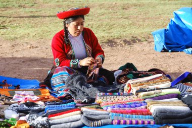 CUSCO PERU 'nun yanında - 15 Kasım 2010' da Cusco Peru 'da geleneksel giysi satışı kıyafetleri içinde renkli masa örtüleri ve kumaşlar giyen kadın. Ulusal kırsal yoksulluk oranı yüzde 50 'nin üzerinde.