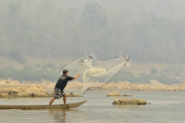1 Nisan 2013 'te Mekong Nehri Laos' ta balık tutmak için balıkçı ağını fırlattı..