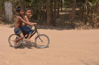 PHEN, CAMBODIA - 23 Mart 2013: Tanımlanamayan sokak çocukları bisiklete biniyor. Sadece Phnom Penh 'de 10 bin ila 20 bin arasında çocuk sokaklarda yaşıyor ve çalışıyor.