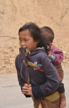 Kamboçyalı kız kardeşiyle yürüyor.