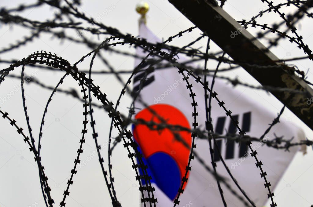 Fence and flag at the Korean Demilitarized Zone is a strip of land running across the Korean Peninsula that serves as a buffer zone between North & South Korea which runs along the 38th parallel north