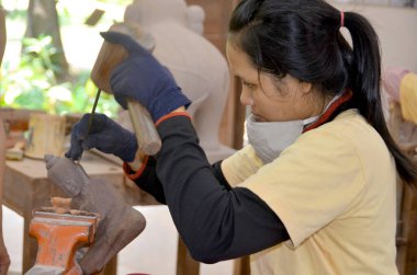 SIEM REAP CAMBODIA - 30 Mart 2013 'te Siem Reap Kamboçya' da küçük Khmer heykelleri oymak için mermer bloktaki araçları kullanan bir oymacı.