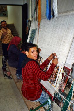 CAIRO EGYPT - 26 Kasım 2008 'de Mısır' da bilinmeyen bir çocuk kilim dokuyor. Okulun yerini bir fabrikanın aldığı ve aydınlıktan karanlığa halı örmeyi öğrendiği bir çocukluk hayal edin..
