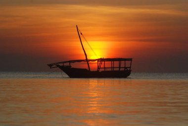 Denizdeki uzun bir günün ardından gün batımında Dhow Boat balıkçıları. Tanzanya 'nın Zanzibar Adası' ndaki Nungwi köyünde çekildi. 