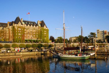VICTORIA, CANADA - 23 Haziran 2009 'da Kanada' nın Victoria kentinden geçen turistlerle birlikte Kanada Bayrağı Fairmont İmparatoriçe Oteli 'nin tepesinde dalgalanır. Bu lüks otel 1908 'de açıldı..