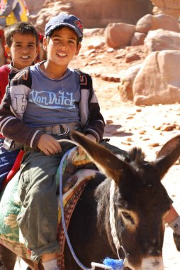 PETRA, JORDAN - 25 Kasım 2009 Petra, Ürdün 'de kimliği belirsiz çocuklar eşeğe binmek için turistleri bekliyor. Yolculuk 20JD tuttu. Petra, Nabataean krallığının etkileyici başkentiydi..