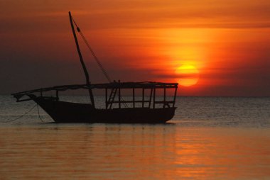 Denizdeki uzun bir günün ardından gün batımında Dhow Boat balıkçıları. Tanzanya 'nın Zanzibar Adası' ndaki Nungwi köyünde çekildi. 