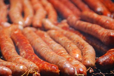 Arka bahçedeki ızgarada sosisler pişiyor.