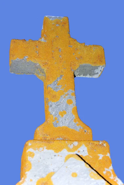 old gravestone with a cross on the background of the sky