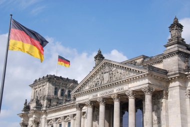 Alman bayrağı Alman parlamento binası önünde dalgalanmakta, Berlin, Almanya 'daki Reichstag.