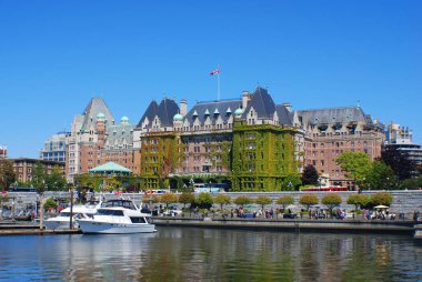 VICTORIA, CANADA - 23 Haziran 2009 'da Kanada' nın Victoria kentinden geçen turistlerle birlikte Kanada Bayrağı Fairmont İmparatoriçe Oteli 'nin tepesinde dalgalanır. Bu lüks otel 1908 'de açıldı.. 