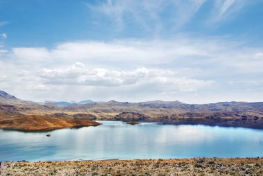 Peru 'nun arka planında, dağlı bir göl ve berrak mavi gökyüzü.