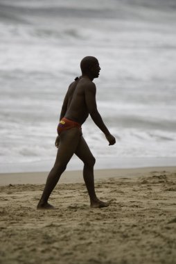 Afrikalı adam deniz sahilinde yürüyor.