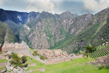 Machu Picchu ya da Machu Pikchu Quechua machu yaşlı, yaşlı, pikchu piramidi; dağ ya da geniş tabanlı ve keskin tepelerle biten bir çıkıntı