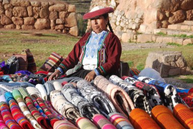 CUSCO PERU 'nun yanında - 15 Kasım 2010' da Cusco Peru 'da geleneksel giysi satışı kıyafetleri içinde renkli masa örtüleri ve kumaşlar giyen kadın. Ulusal kırsal yoksulluk oranı yüzde 50 'nin üzerinde. 
