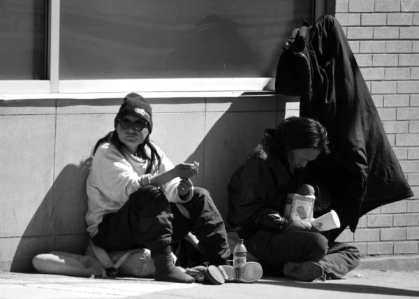 ホームレスのカップルが街の通りに座っている — ストック写真
