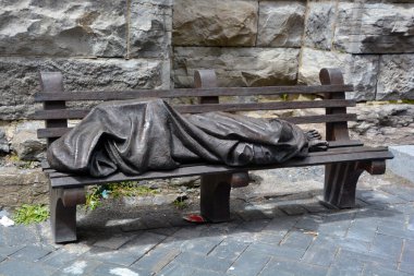 MONTREAL CANADA - 05 07 2020: Evsiz İsa, Kanadalı heykeltıraş Timothy Schmalz tarafından parktaki bankta uyuyan bir evsiz olarak tasvir edilen bronz heykel..
