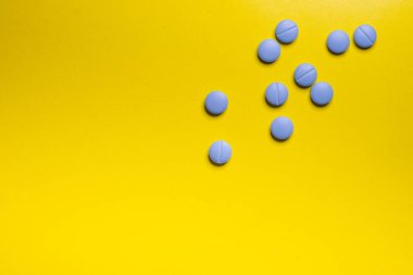 Sarı arka plana karşı mavi hapların yakın çekimi. İzole edilmiş kavram.