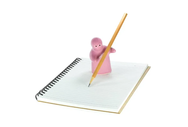 Ceramiczne zabawki jest pisanie na Notatnik, który na białym tle — Zdjęcie stockowe