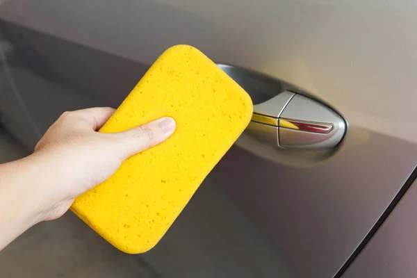 Hand cleaning car\'s dirt with sponge.