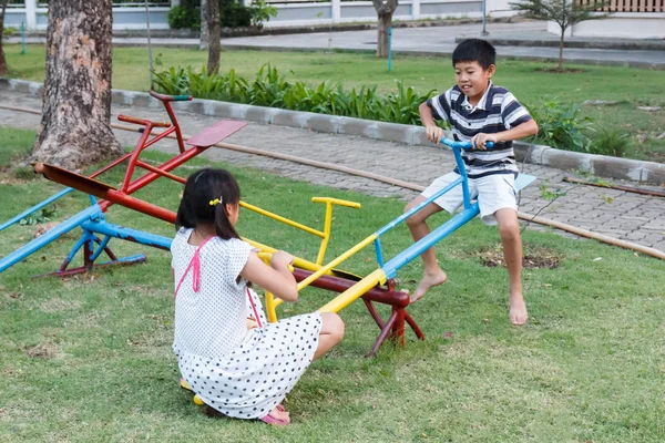 Brother and sister play seesaw. — Stock Photo, Image
