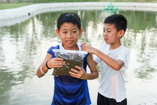 Thailändischer Zwillingsjunge bereitet sich auf Fischfutter vor. lizenzfreie Stockbilder