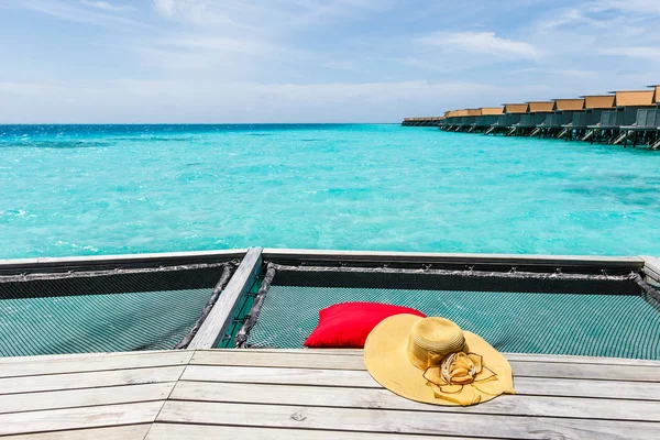 Sombrero y almohada en la red sobre el mar . — Foto de Stock