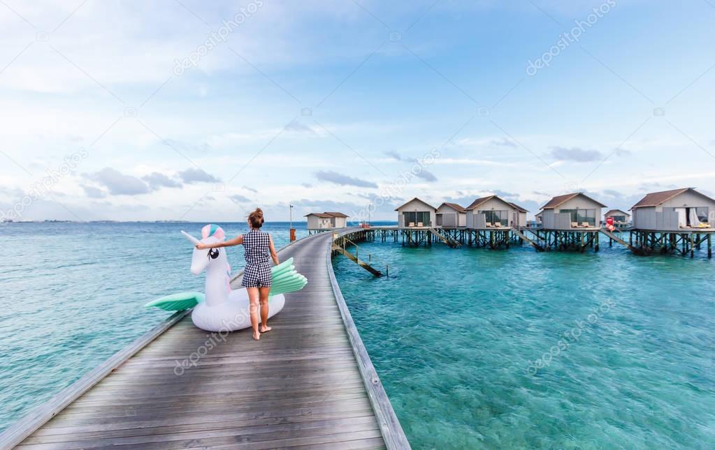 Asian woman holding pegasus pool float at Maldives.
