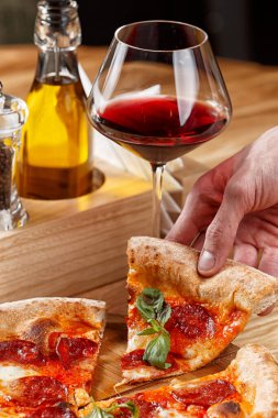 Biberli pizza ve ahşap masada bir bardak şarap.