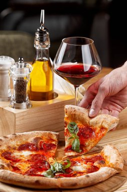 Biberli pizza ve ahşap masada bir bardak şarap.