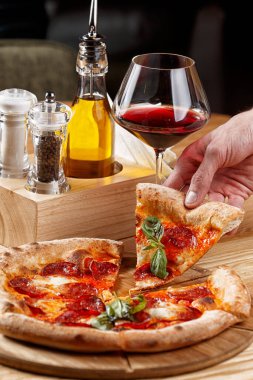 Biberli pizza ve ahşap masada bir bardak şarap.
