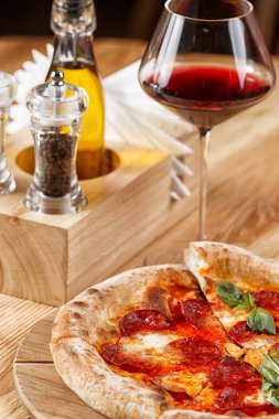 Biberli pizza ve ahşap masada bir bardak şarap.